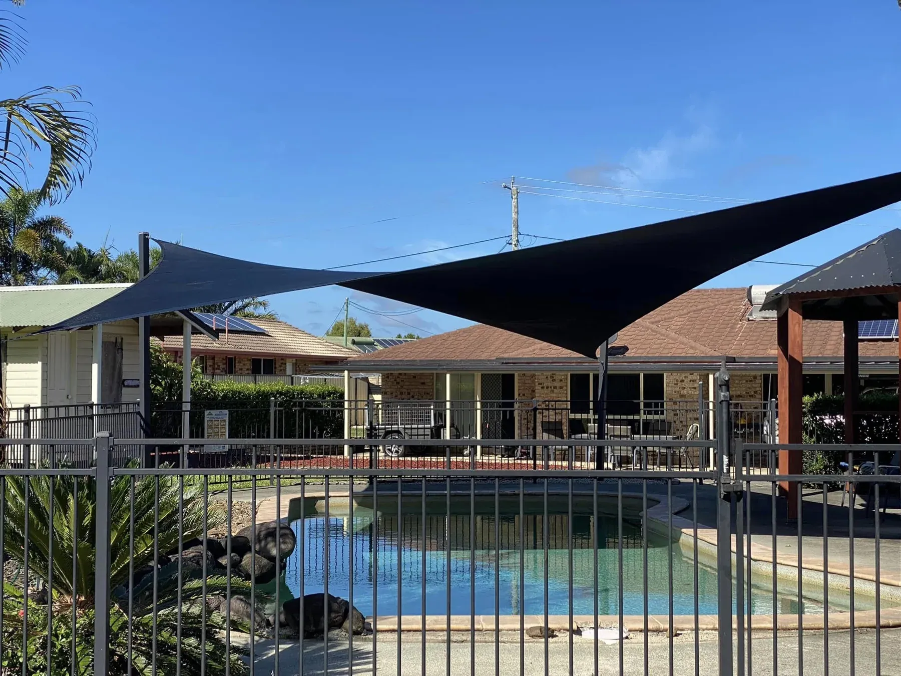 Actual Shades2U pool installation with sculptural dark sails