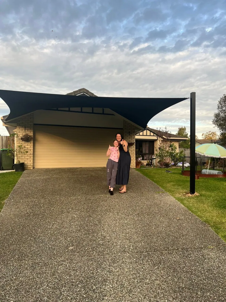 A lady and girl at home beneath their completed Shades2U carport